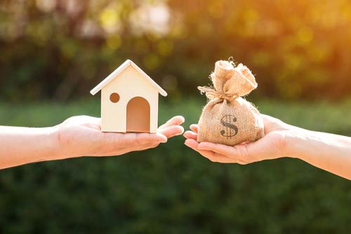 hands holding small house and bag of money